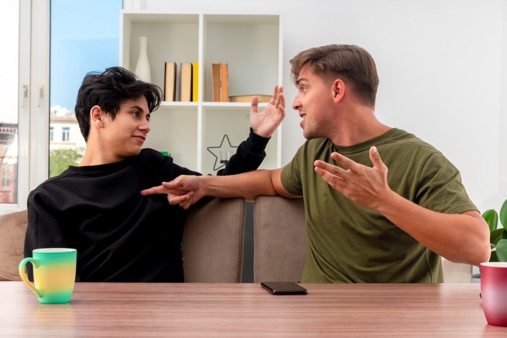 兩個男人坐在沙發上聊天，似乎討論著要麻煩別人的事