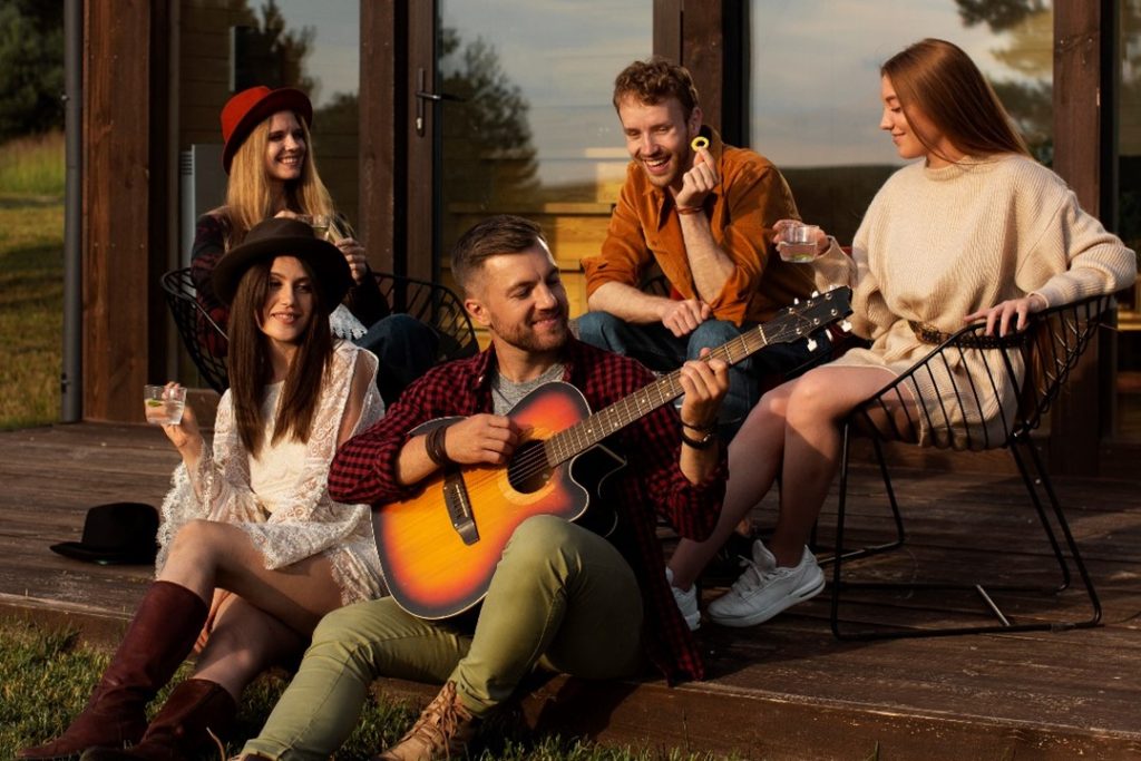 三五好友聚在一起，其中一位男生抱著吉他彈奏著，照片敘說獨有的過節儀式