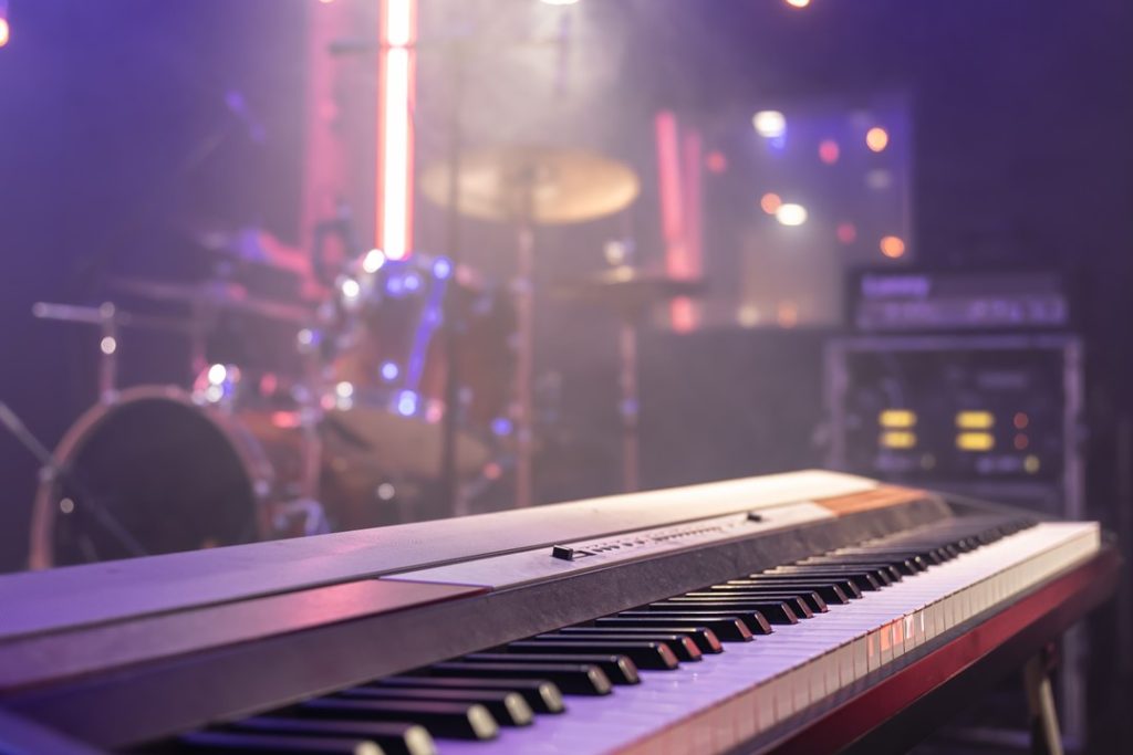 一台電子琴在畫面的前方，後方為一套爵士鼓及調音設備，彷彿要演奏振奮人心的開場或結尾音樂